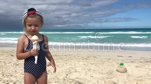 穿泳衣的小女孩在海滩上吃冰淇淋视频的预览图