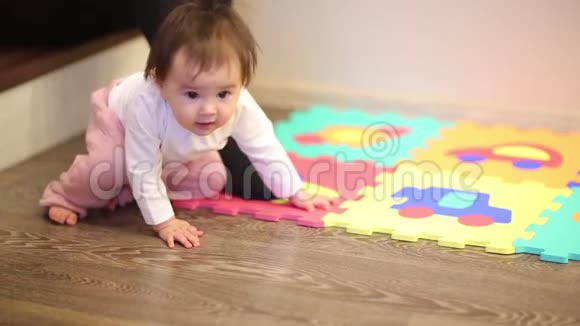 一个可爱的小女孩坐在一边在家里拿着五颜六色的拼图游戏垫和数字视频的预览图