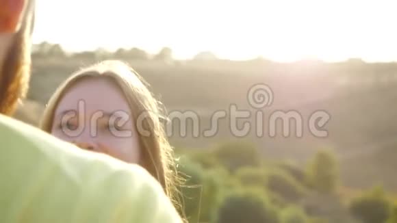 在一个温暖的秋天一个留着胡子的年轻人在一片荒芜的草地上亲吻他的爱人一对年轻夫妇的特写镜头视频的预览图