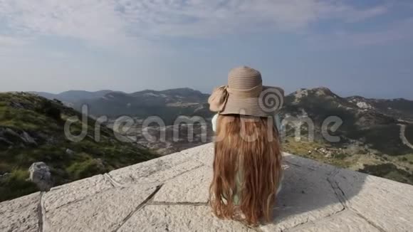 山顶上的女孩坐着欣赏风景视频的预览图