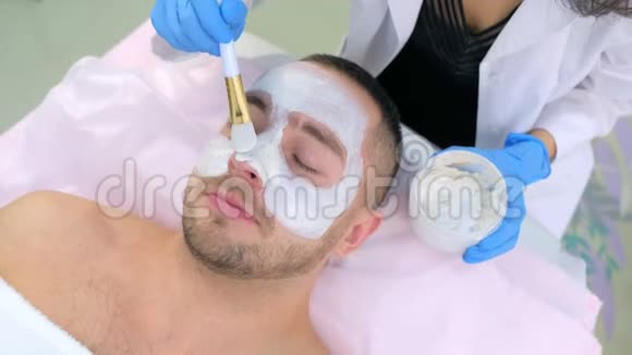 美容师正在美容诊所用白色面膜敷脸特写视频的预览图