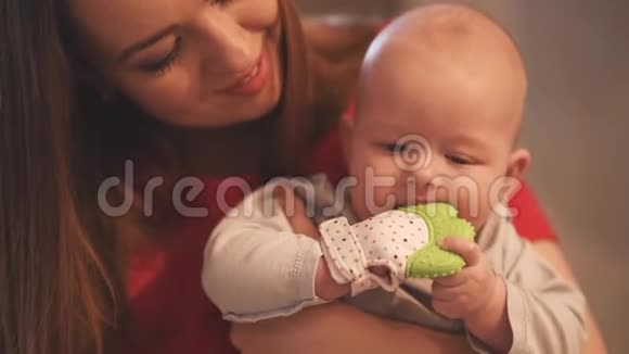 妈妈抱着一个孩子在怀里刚出生的无牙婴儿咬玩具视频的预览图