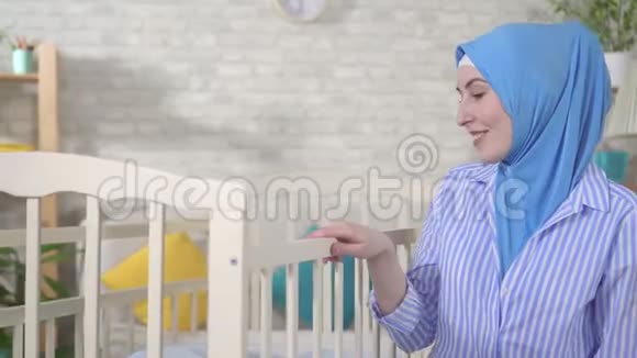 穆斯林年轻女子在托儿所的床边做母亲视频的预览图