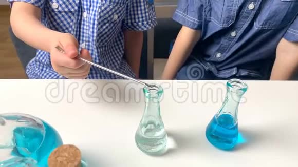 孩子们小学生把有色液体倒入玻璃瓶中从吸管和注射器中滴出早期概念视频的预览图