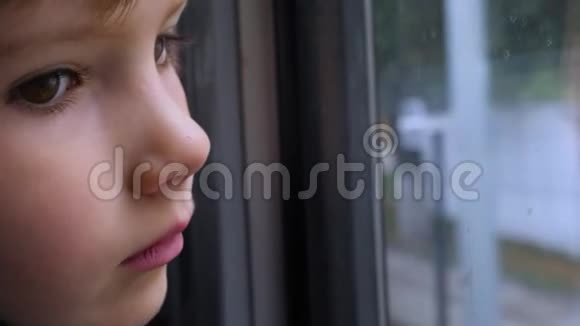 孩子透过窗户看一个小孩在火车上向窗外看的特写镜头特写后侧景视频的预览图