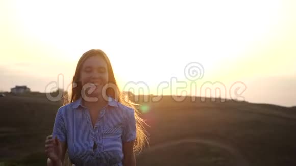 穿着一件衣服的漂亮少女在一片温暖的秋田里奔跑背景是田野里的夕阳视频的预览图