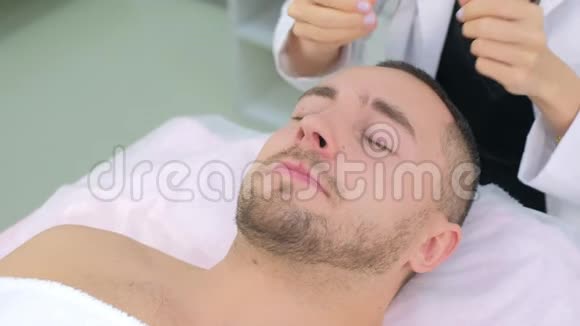 美容师女士正在给男人病人的脸涂上泡沫化的乳液以清洁视频的预览图