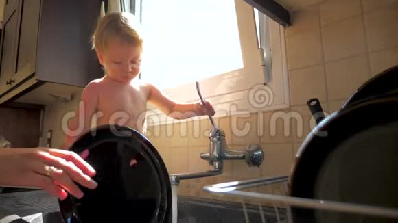 妈妈带着两岁的孩子洗盘子母亲节厨房清洁休闲生活系列图片视频的预览图
