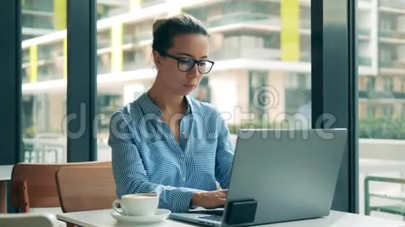 漂亮的女士在咖啡馆里操作笔记本电脑视频的预览图