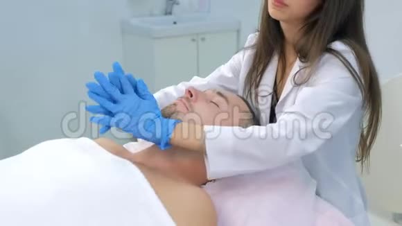 戴手套的美容师正在给病人颈部按摩皮肤涂霜视频的预览图