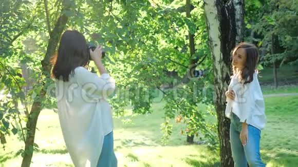 两个漂亮的女孩在阳光明媚的天气里在新鲜空气中拍照一对穿白色衬衫的性感女孩的近景视频的预览图
