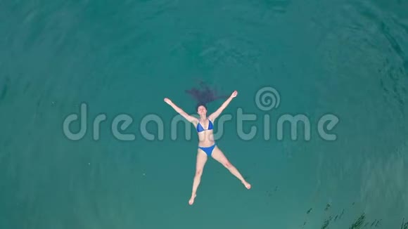 一个穿着泳衣的女人仰卧在蓝色的湖中游泳视频的预览图