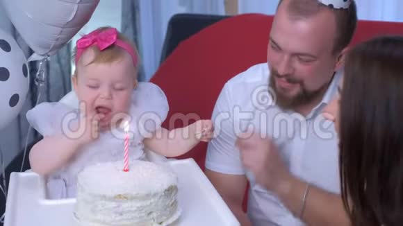 家庭肖像妈妈爸爸和小女孩在一岁生日蛋糕和蜡烛视频的预览图