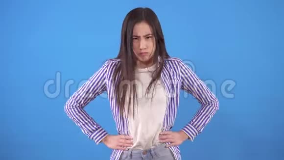 年轻闷闷不乐的亚洲女人站在蓝色的背景上用手指否认视频的预览图