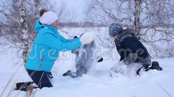 妈妈和孩子们互相扔雪在冬天的公园里尽情享受冬天在公园散步他的笑声和欢乐视频的预览图