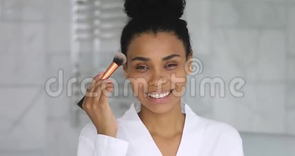 微笑迷人的非洲女人手握刷子涂粉视频的预览图
