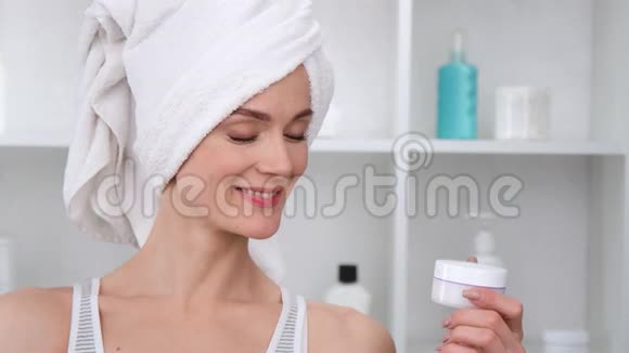 微笑的女人在毛巾与完美的皮肤持有奶油罐中型近距离拍摄4k红色相机视频的预览图