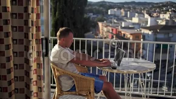 自由职业者坐在阳台上用笔记本电脑工作视频的预览图