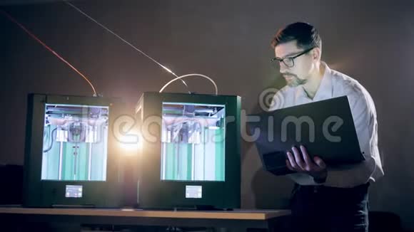 男工程师正在用笔记本电脑控制3D打印机在3D打印实验室使用3D打印机的人视频的预览图