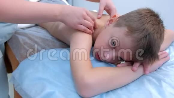 医生按摩师为临床上的青少年男孩做治疗按摩视频的预览图
