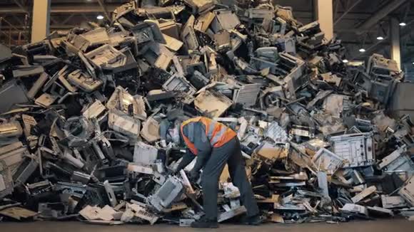 一个垃圾场的工人正在整理办公室机器的碎片视频的预览图