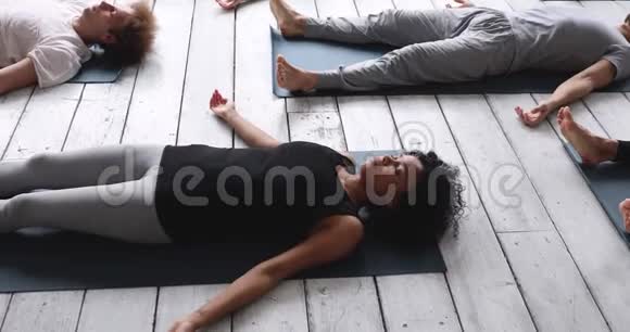 在室内瑜伽课上练习萨瓦萨纳姿势的非洲妇女视频的预览图