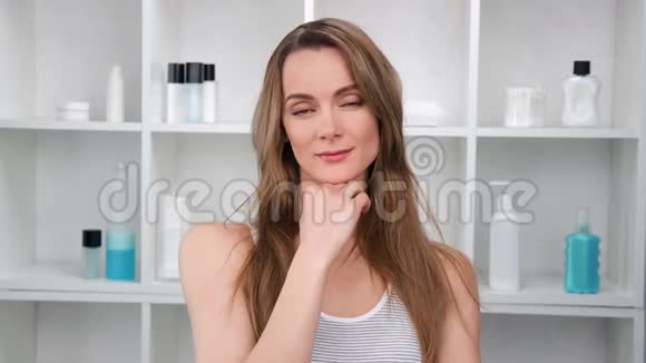 迷人的顽皮女人微笑在浴室享受晨间护肤特写拍摄于红色相机视频的预览图