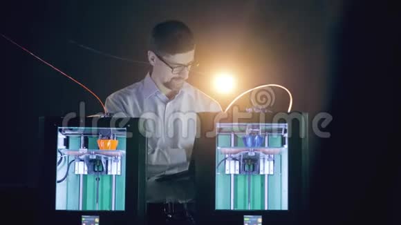 两个3D打印机在一个黑暗的房间里工作有一个男工程师视频的预览图