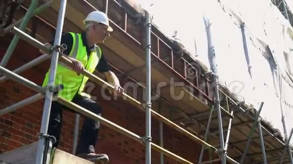 建筑工地站在脚手架上的男建筑工头工人测量员或建筑师视频的预览图