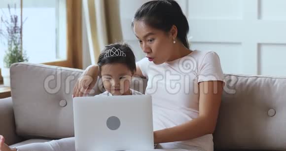 亚洲母亲用笔记本电脑教小女儿接受儿童教育视频的预览图