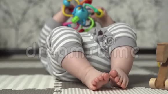 婴儿的脚在框架里穿条纹睡衣的孩子在地板上和一个彩色玩具的孩子玩视频的预览图