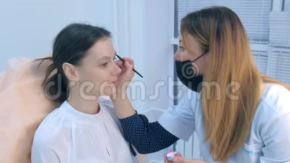 美容师在涂饰前对妇女眉毛进行铅笔涂饰视频的预览图