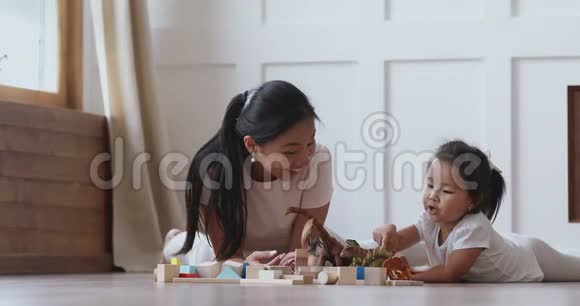 快乐的亚洲妈妈和小女儿在地板上玩恐龙视频的预览图