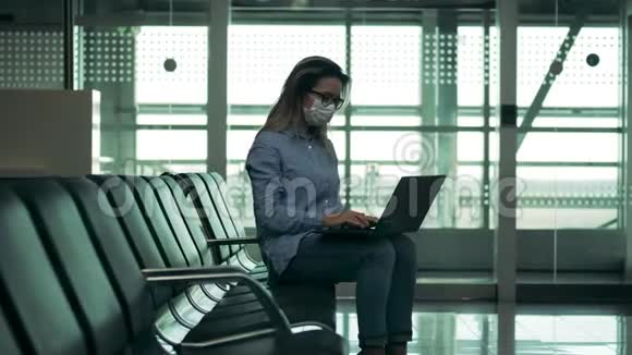 一名戴着安全面罩的妇女正在机场操作一台笔记本电脑视频的预览图