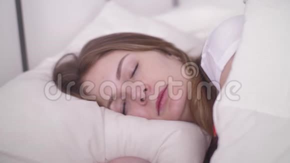 年轻女性睡在舒适的床上睡在舒适的白色枕头上健康的深度睡眠视频的预览图