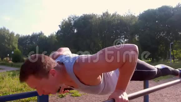 肌肉运动员健美运动员体操运动员正在城市公园的酒吧里做俯卧撑视频的预览图