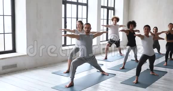 多种文化的女孩和男子表演战士IIViabhadrasana瑜伽姿势视频的预览图