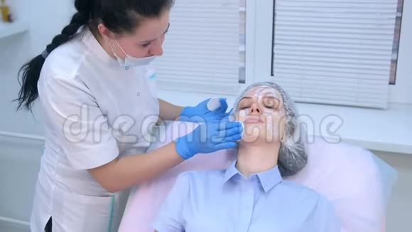 美容师用麻醉剂从面部擦拭霜然后再进行生物消毒视频的预览图