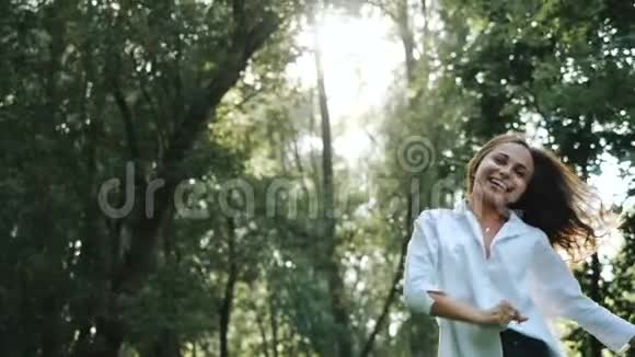 一个穿着白色衬衫和长发的年轻漂亮女孩的正面景色她正看着相机蹦蹦跳跳地寻找一个漂亮的女孩视频的预览图