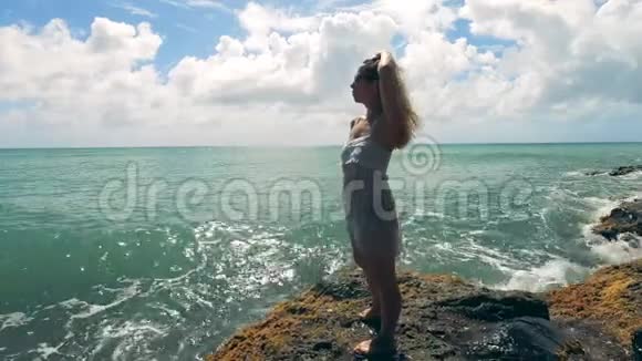 一位女士站在靠近大海的岩石上享受着视频的预览图