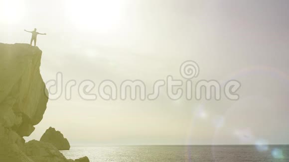一位男性游客站在悬崖边张开双臂欣赏风景的剪影视频的预览图