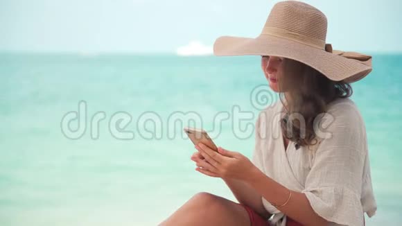 一个戴着大草帽的年轻女人用她的智能手机视频的预览图