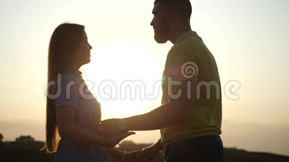 幸福美丽的年轻夫妇牵着手在夕阳的映衬下深情地看着对方视频的预览图
