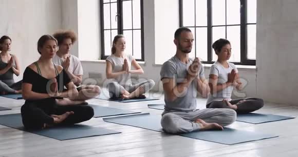 在室内练习瑜伽时坐在莲花姿势中的不同的人冥想视频的预览图