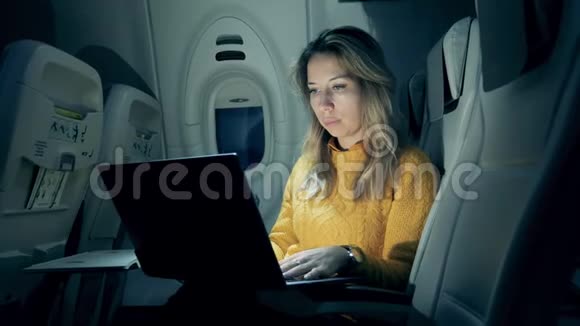 夜间飞行期间一位漂亮女士在笔记本电脑上打字视频的预览图