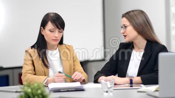 两位面带微笑的女商务人员在办公室讨论工作进行职业面试视频的预览图