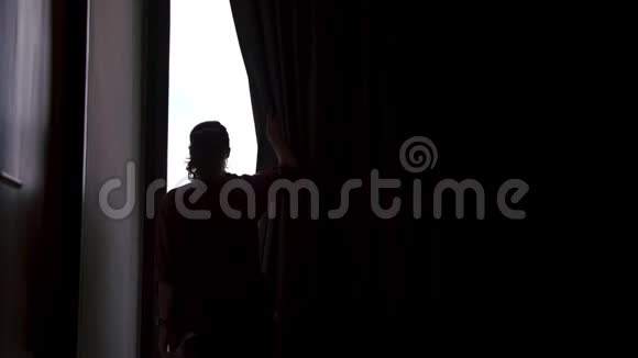 一个年轻的女人打开窗帘视频的预览图