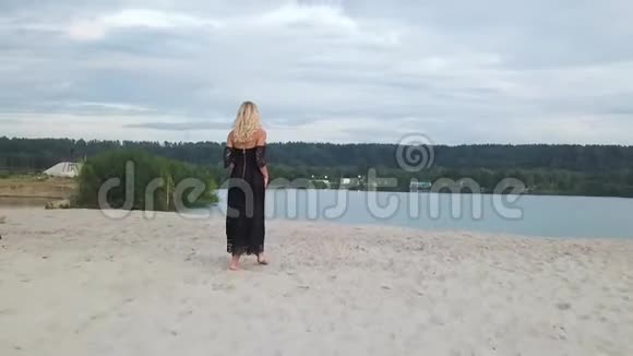 沙滩上穿着黑色裙子的金发女人视频的预览图