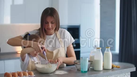 妈妈在教她的小女儿如何在家里的厨房里做饭视频的预览图