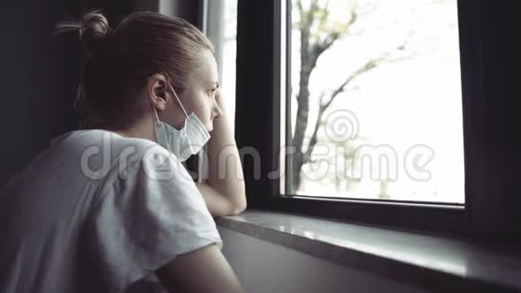 窗户旁戴防护医疗面罩的妇女视频的预览图